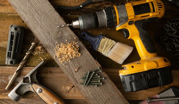 A few DIY tools on a table, with a piece of wood and some wood shavings.