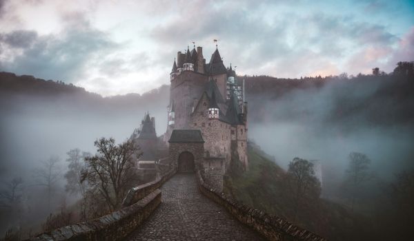 A photo of a small castle surrounded by a light mist.