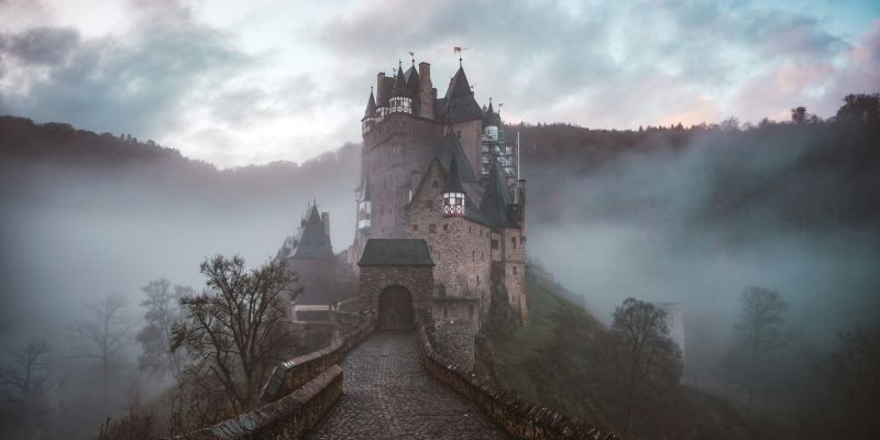 A photo of a small castle surrounded by a light mist.