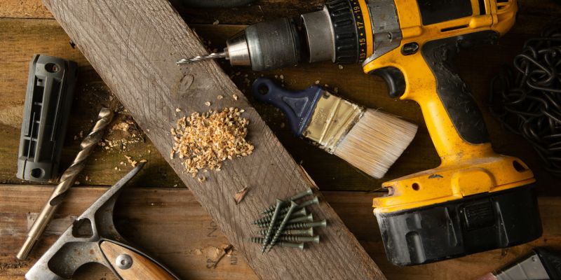 A few DIY tools on a table, with a piece of wood and some wood shavings.